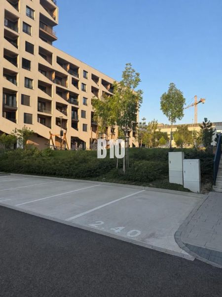 Parking spaces in front of a residential building in Bratislava V, surrounded by greenery and trees.