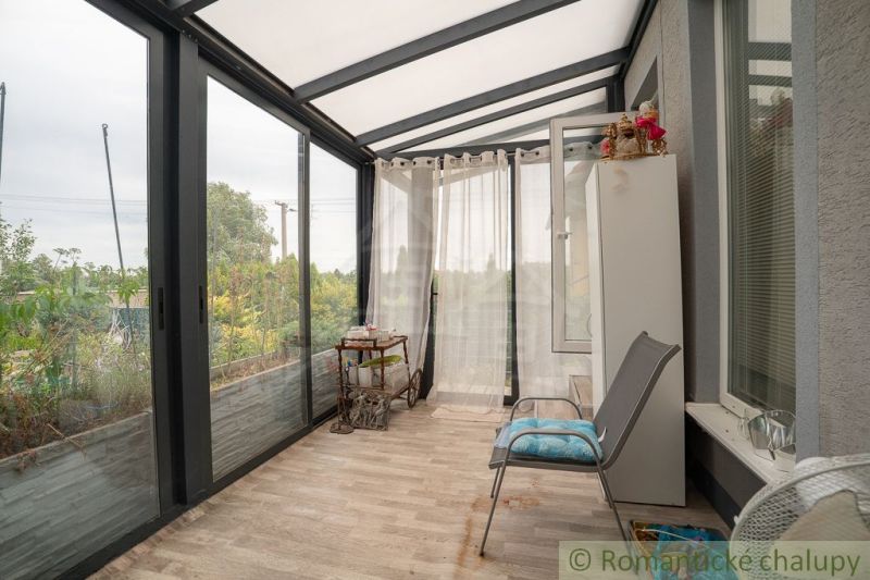 A glazed veranda with a wooden decor floor in a cottage.
