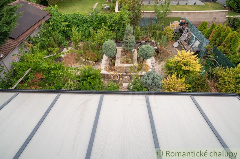 A garden by the cottage in Senec with rich greenery and a greenhouse.