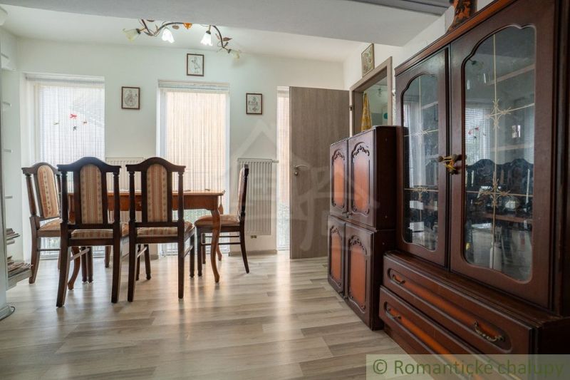 A dining room in a cabin with wooden floor decor, featuring elegant furniture and natural light.