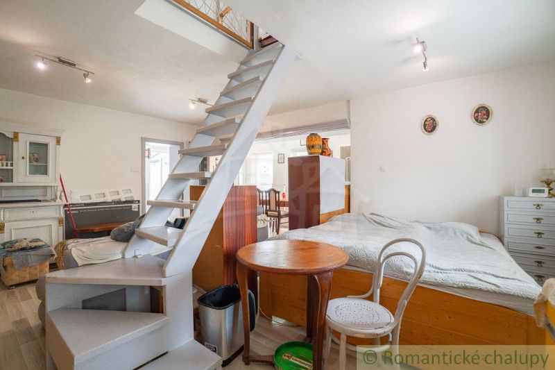 Interior of a cabin with a narrow staircase, bed, table, and floor with wooden decor.