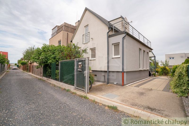 The exterior of the cottage in Senec with a paved driveway and lush vegetation.
