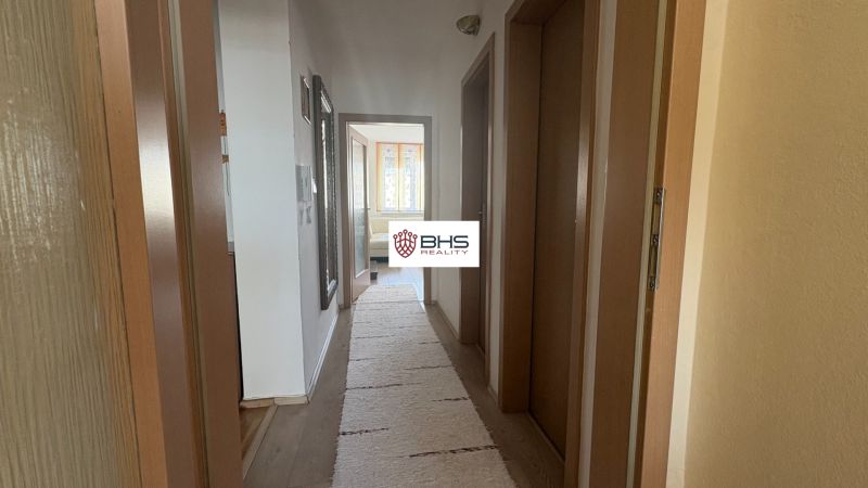 A hallway in a 2-room apartment with a wooden decor floor and a mirror on the wall.