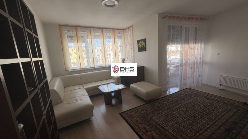 Living room with wood-patterned flooring, a corner sofa, and a carpet in a two-room apartment.