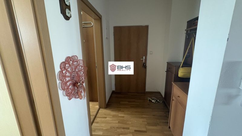 A hallway in a 2-room apartment with a wooden decor floor and a coat rack.