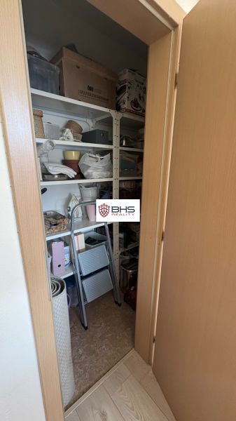 Storage space in a 2-room apartment includes shelves with various items and a folding ladder.