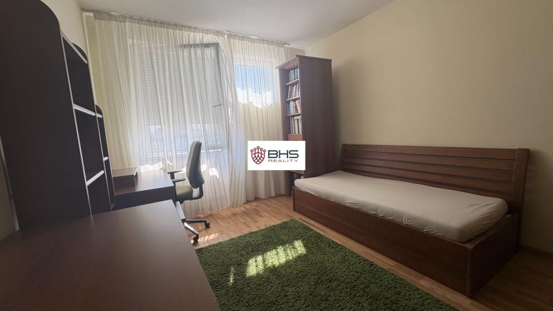 Bedroom with a bed, desk, and wooden decor flooring in a two-room apartment.