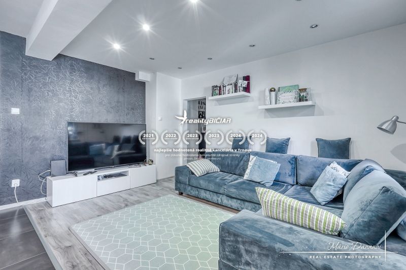 Living room in a 3-room apartment with a large TV, comfortable sofa, and wooden decor flooring.