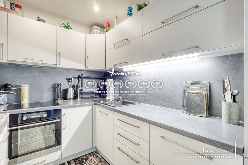 A kitchen in a studio apartment with white cabinets and appliances on the countertop.
