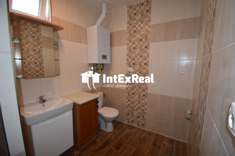Bathroom with toilet, sink, boiler, and wooden decor flooring in commercial premises.