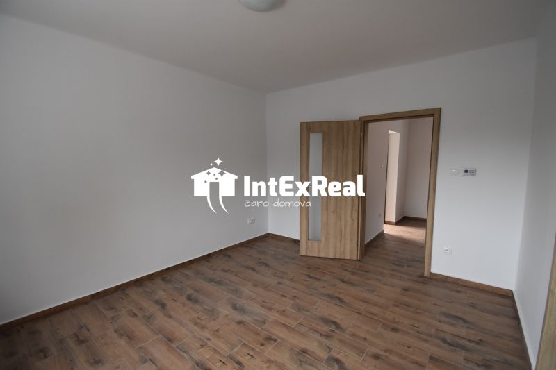 Interior of commercial spaces with white walls and wood-patterned flooring.