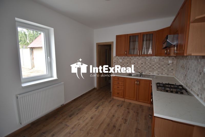 A kitchen in commercial premises with a wood-patterned floor and a gas stove.
