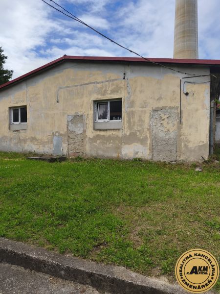 A building of warehouses and halls in Žiar nad Hronom with shabby walls and a grassy area.