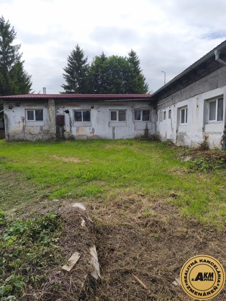 The exterior of older warehouses in Žiar nad Hronom, surrounded by greenery and trees.