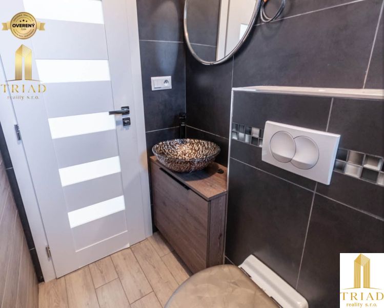 A bathroom in a family house with a designer sink and a floor with a wooden decor.