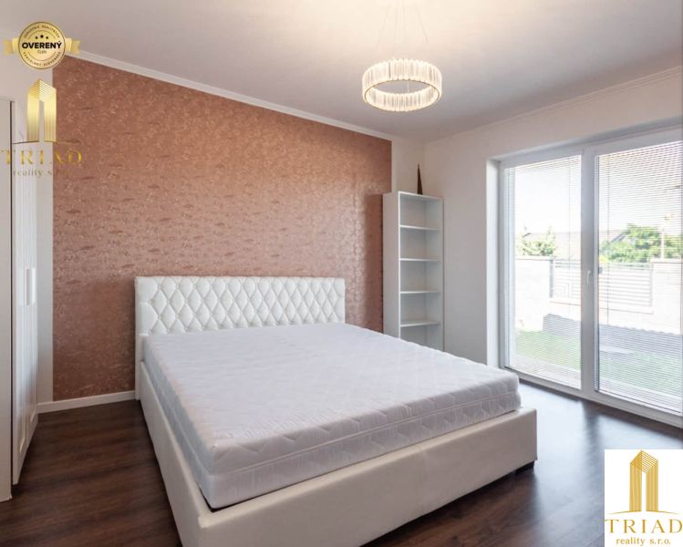 Bedroom in a family house with a double bed, wooden decor flooring, light wallpaper.