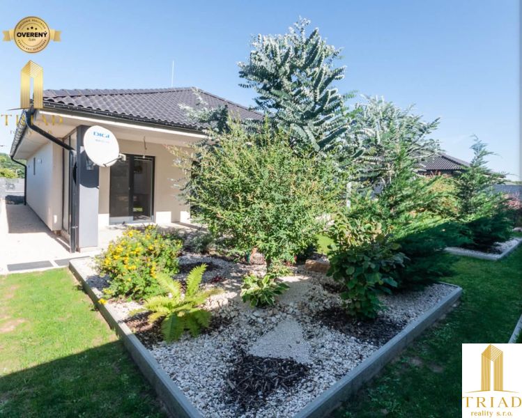 A family house in Bajč with a landscaped garden and a satellite dish.
