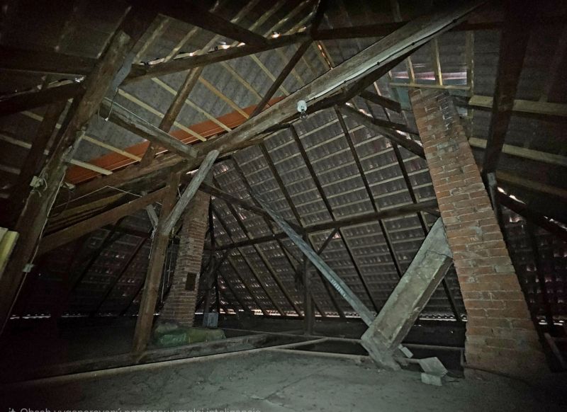 Attic in a family house with roof beams and a brick chimney.