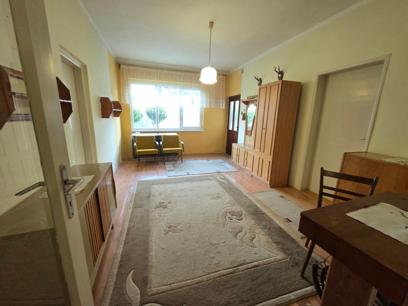 The interior of a family house with carpet, wood-patterned flooring, and wooden furniture.