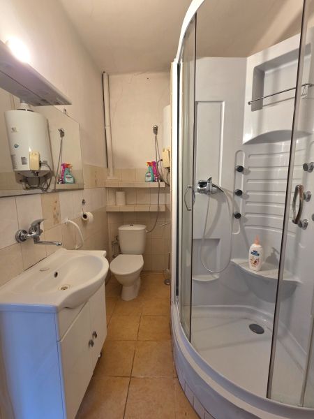 A bathroom in a family house with a toilet, sink, and shower, with light tiles.