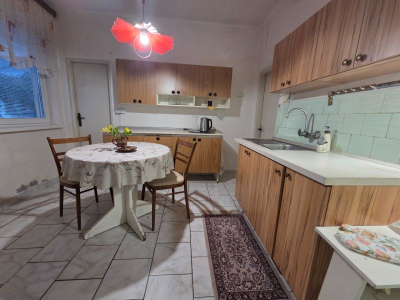 A kitchen in a family house with wooden cabinets and a table with a tablecloth.