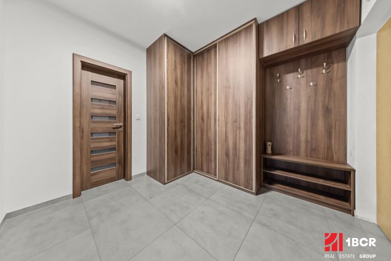 A hallway in a 2-room apartment with a wooden decor floor and a built-in wardrobe.