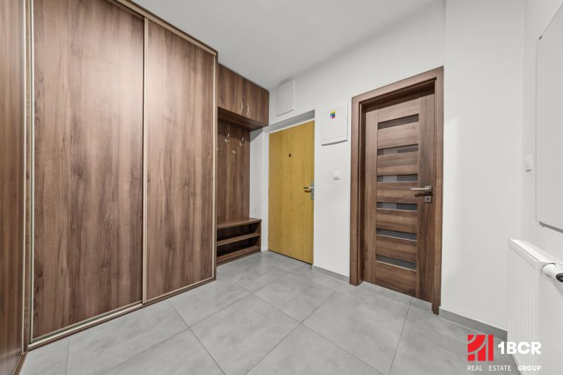 Entrance hall in a 2-room apartment with wood-patterned flooring and storage spaces.