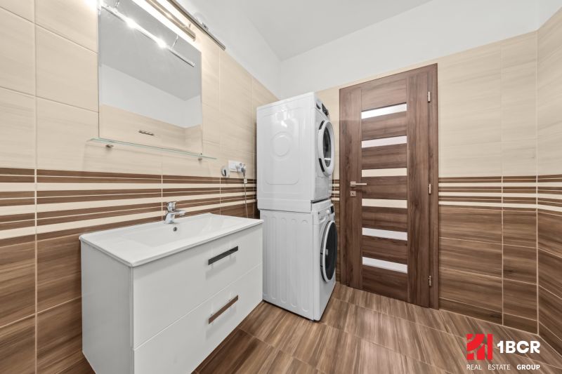 Bathroom with a washing machine and dryer in a 2-room apartment, floor with wooden decor.