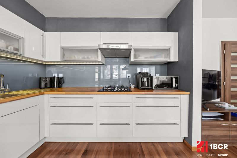 A kitchen in a 2-room apartment with a wooden decor floor and light furniture.