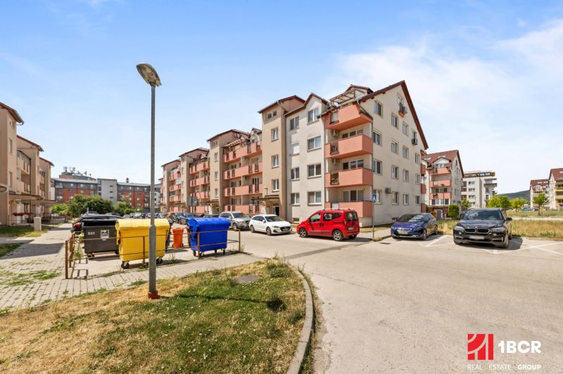 Don Sandtner Street in Pezinok with apartment buildings and a parking lot; ideal for a 2-room apartment.