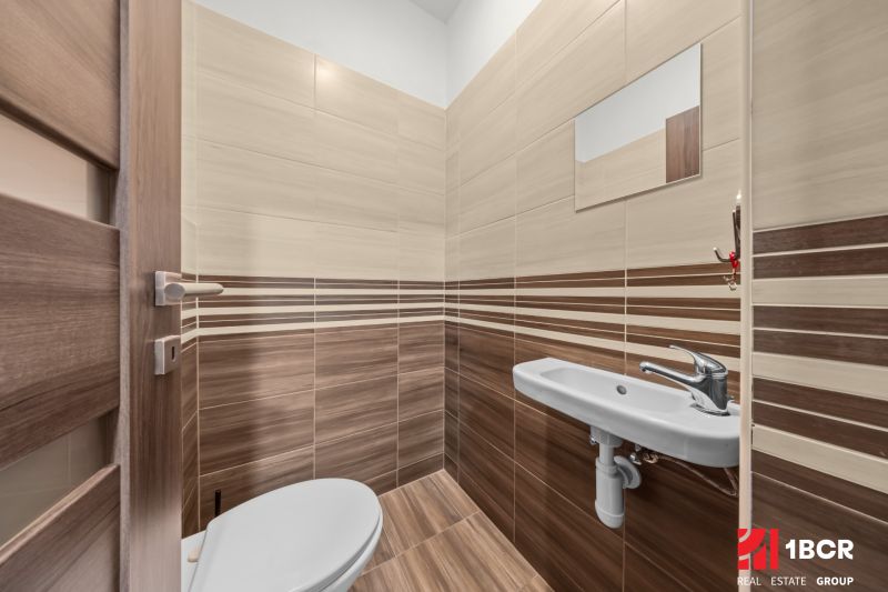 A bathroom with a wooden decor floor and a sink in a 2-room apartment.