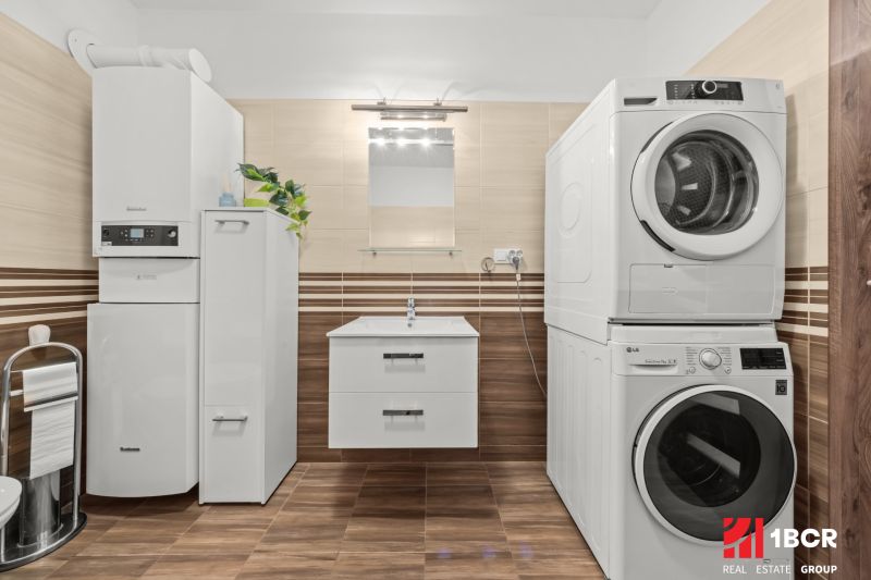 Bathroom with a washing machine and dryer, cabinet, and wooden decor flooring in a 2-room apartment.