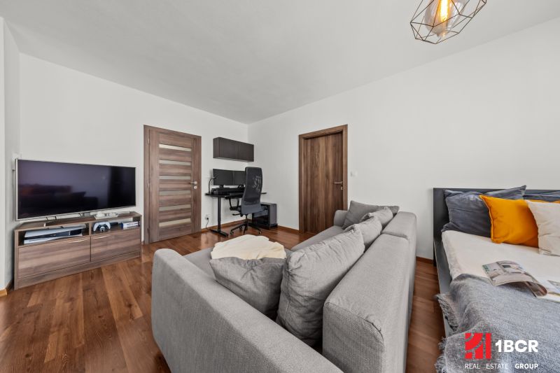 Living room with a sofa, TV, and a work corner in a 2-room apartment.
