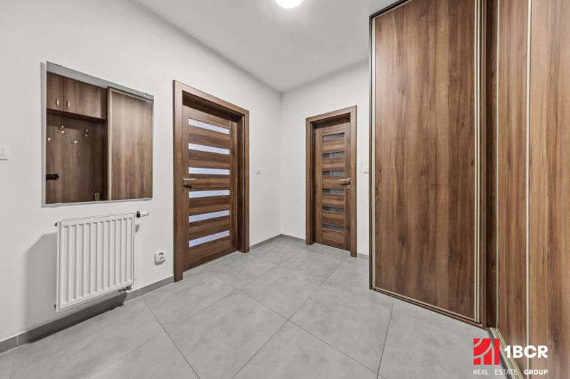 A hallway with built-in wardrobes in a 2-room apartment with a wooden decor floor.