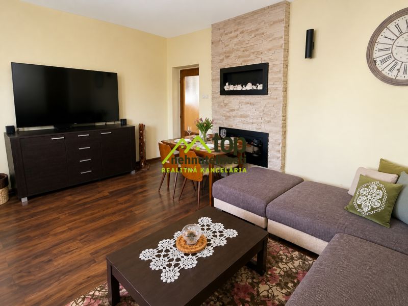 Living room in a family house with a wooden decor floor, a sofa, and a large television.