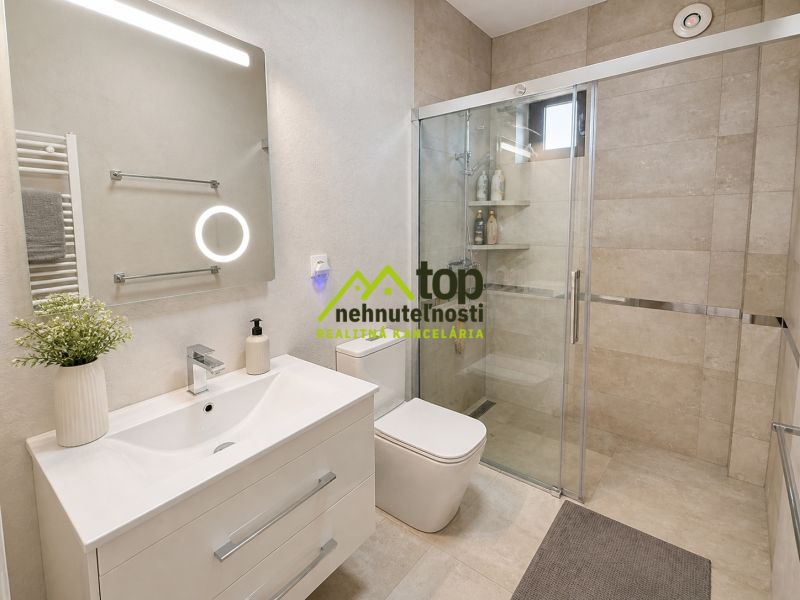 A bathroom in a family house with a sink, shower, and LED lighting.