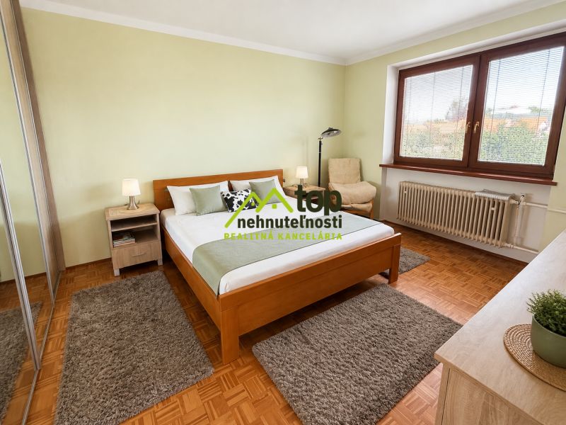 Bedroom with a light wall, bed, and floor with wooden decor, in a family house.