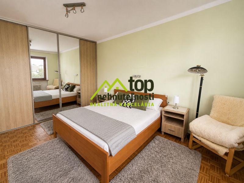 Bedroom with a bed, wardrobe, and wooden decor flooring in a family house.
