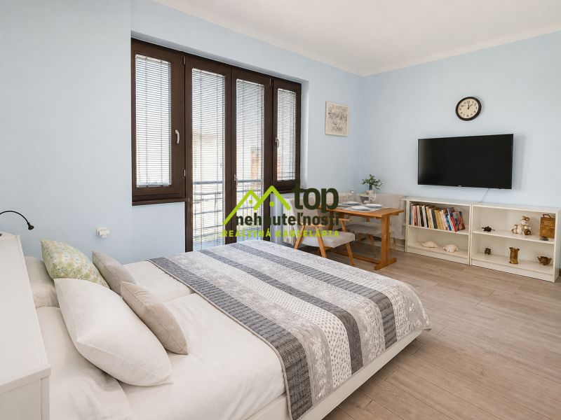Bedroom in a family house with a bed, TV on the wall, and shelves.