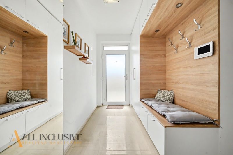 A hallway in a 3-room apartment with built-in seating and a floor with a wood decor.