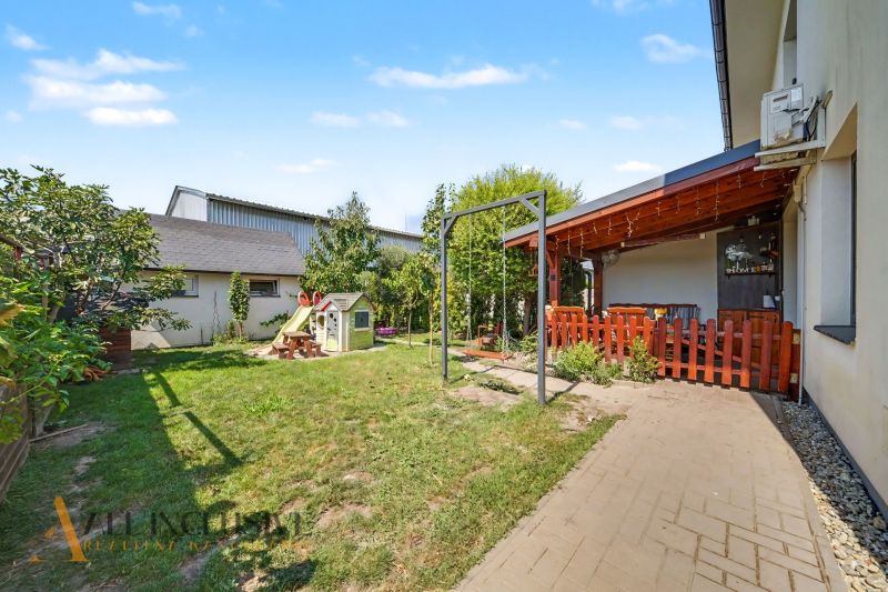 The yard of a 3-room apartment in Veľký Meder with a terrace, swing, and children's playhouse.