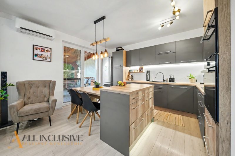 A kitchen in a 3-room apartment with a wooden decor floor, elegant lighting, and designer furniture.