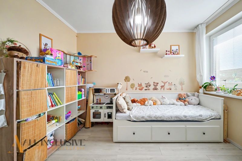 Children's room with a shelf, bed, and toys, floor with wooden decor.