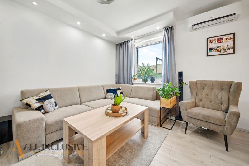 Living room in a 3-room apartment with a sofa, an armchair, and a table, light color palette.