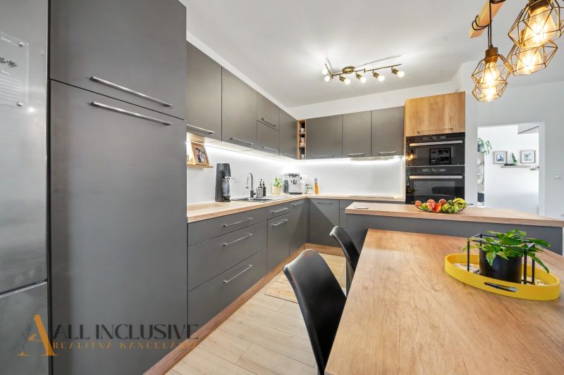 A kitchen in a 3-room apartment with dark cabinets and a wooden decor floor.