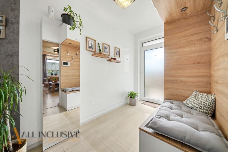 The entrance hall of a three-room apartment with a wooden decor floor and plants.