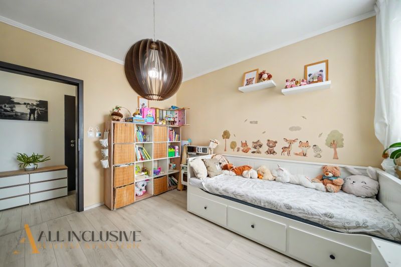 Children's room in a three-room apartment with a wall decorated with animals, a bed, and a bookshelf.