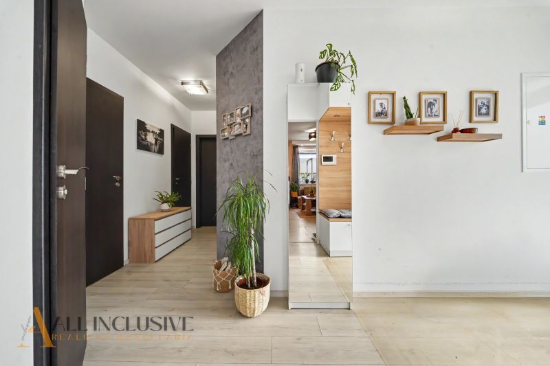 The entrance hall in a 3-room apartment with a wooden decor floor and houseplants.