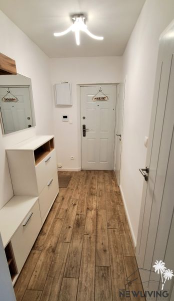 A hallway in a 2-room apartment with a floor featuring a wood decor and white walls.