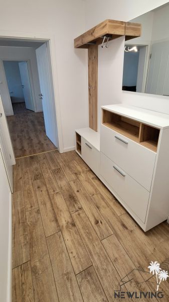 A hallway in a 2-room apartment with a wardrobe and a floor with a wooden decor.
